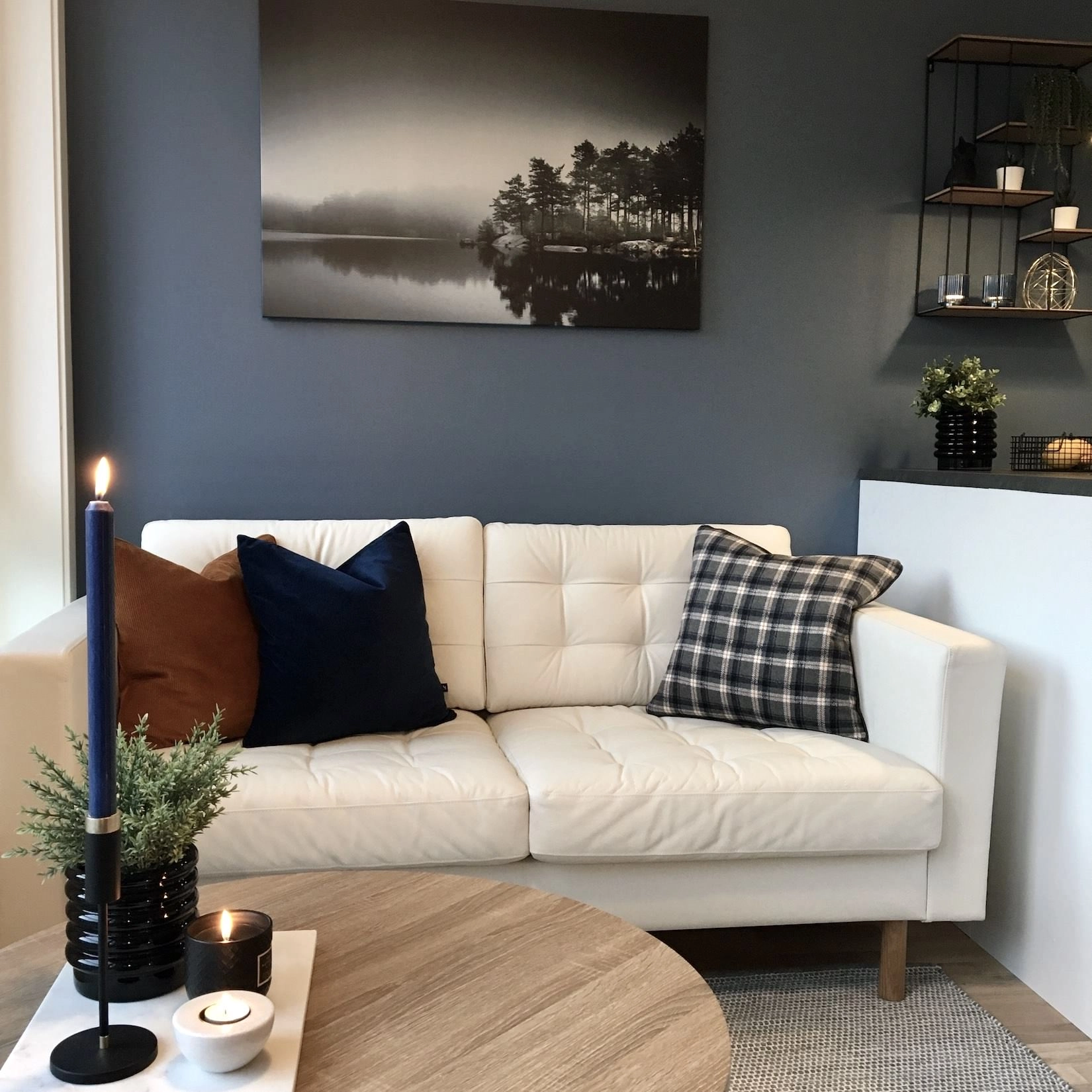 Stue med mørk vegg, stearinlys og lyst sofagruppe, innredet av Langen Interiør på Lade i Trondheim